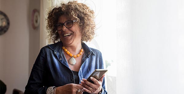 Photo of a lady laughing and holding a mobile phone in her hand