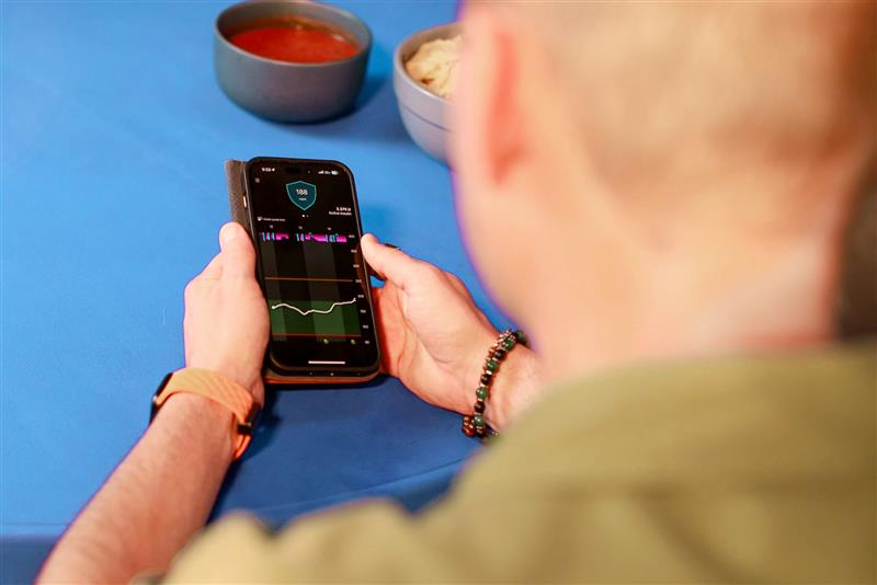 Person holding phone with screen showing MiniMed Mobile app
