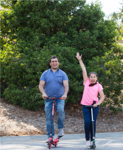 father and daughter riding scooters