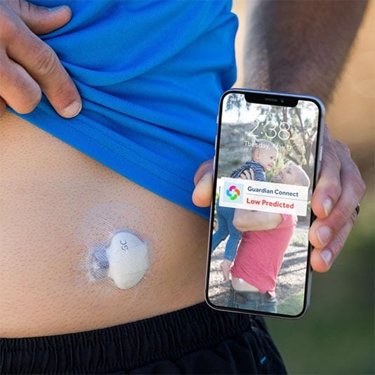 Image of person holding a phone with a Guardian™ sensor on their tummy