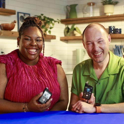 Woman and man smiling and holding MiniMed insulin pumps
