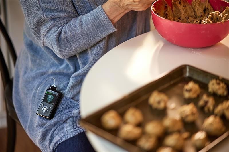 Person making cookies with MiniMed 780G insulin pump clipped to sweater