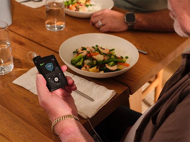 Main looking at MiniMed 780G pump during a meal