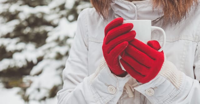 mitten hands holding mug in winter