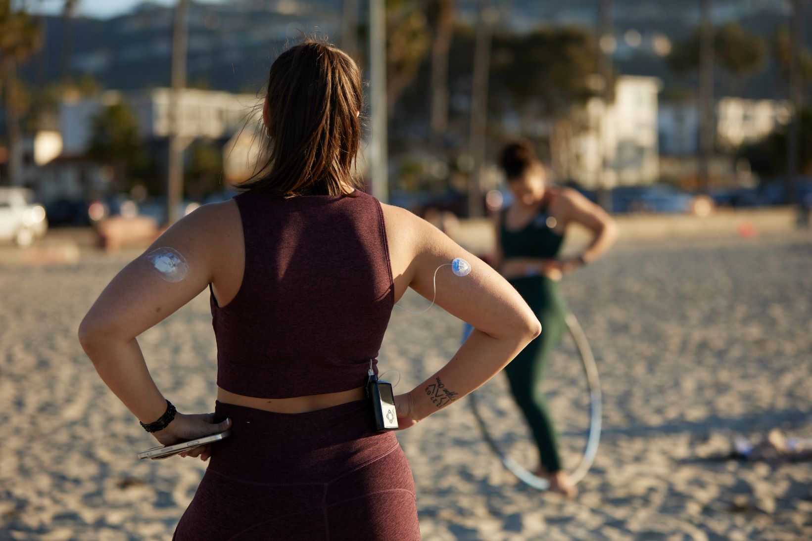 Woman on the beach with CGM and infusion sets on arms