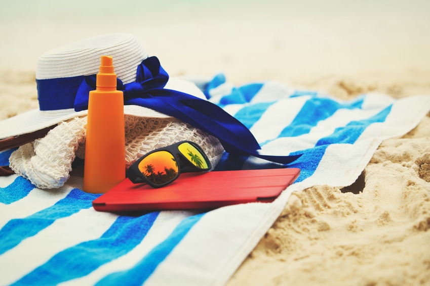 Hat, sunglasses, lotion and tablet on beach tower