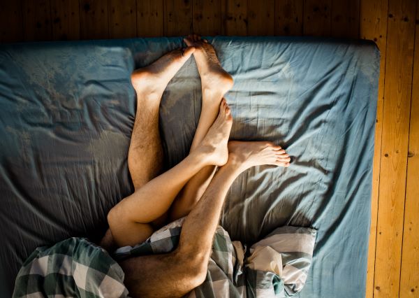man and woman legs in bed